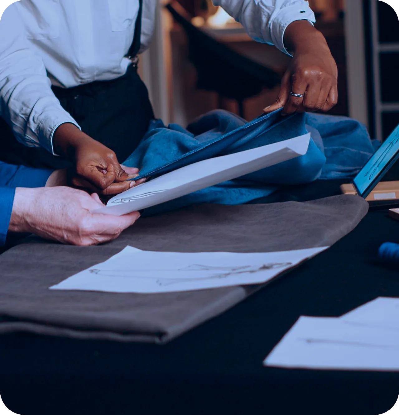 Designers reviewing a technical sketch over fabric samples