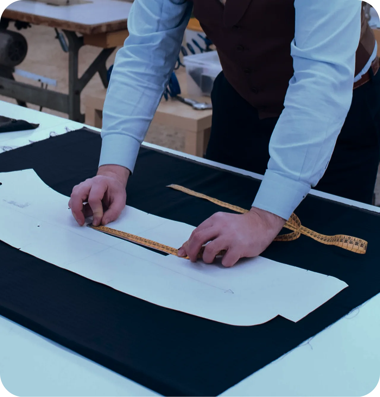 Pattern maker measuring a paper pattern laid over fabric